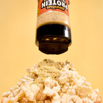 Protein powder being sprinkled onto popcorn with a yellow background