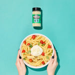 Bowl of pasta with a protein supplement jar on a teal background