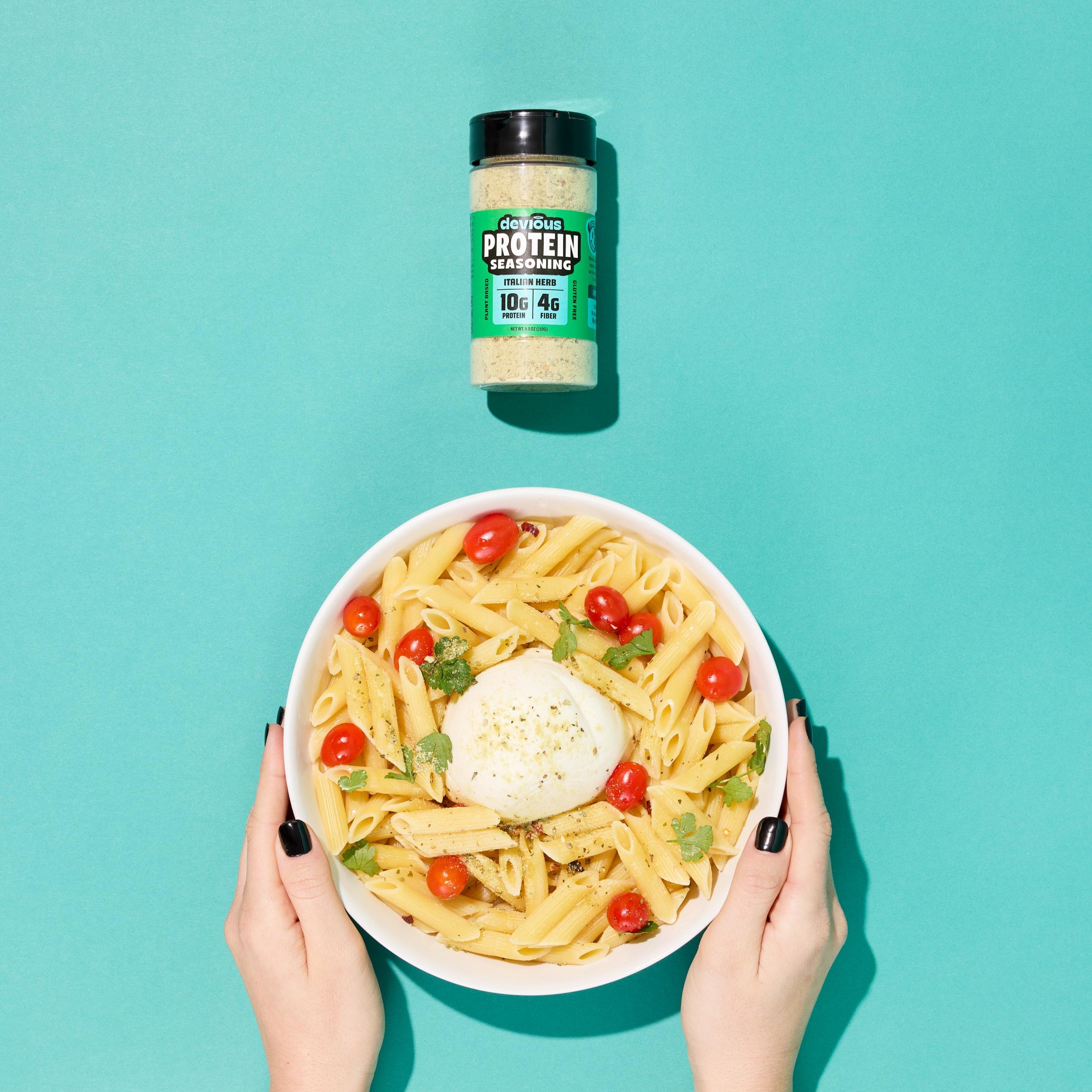 Bowl of pasta with a protein supplement jar on a teal background